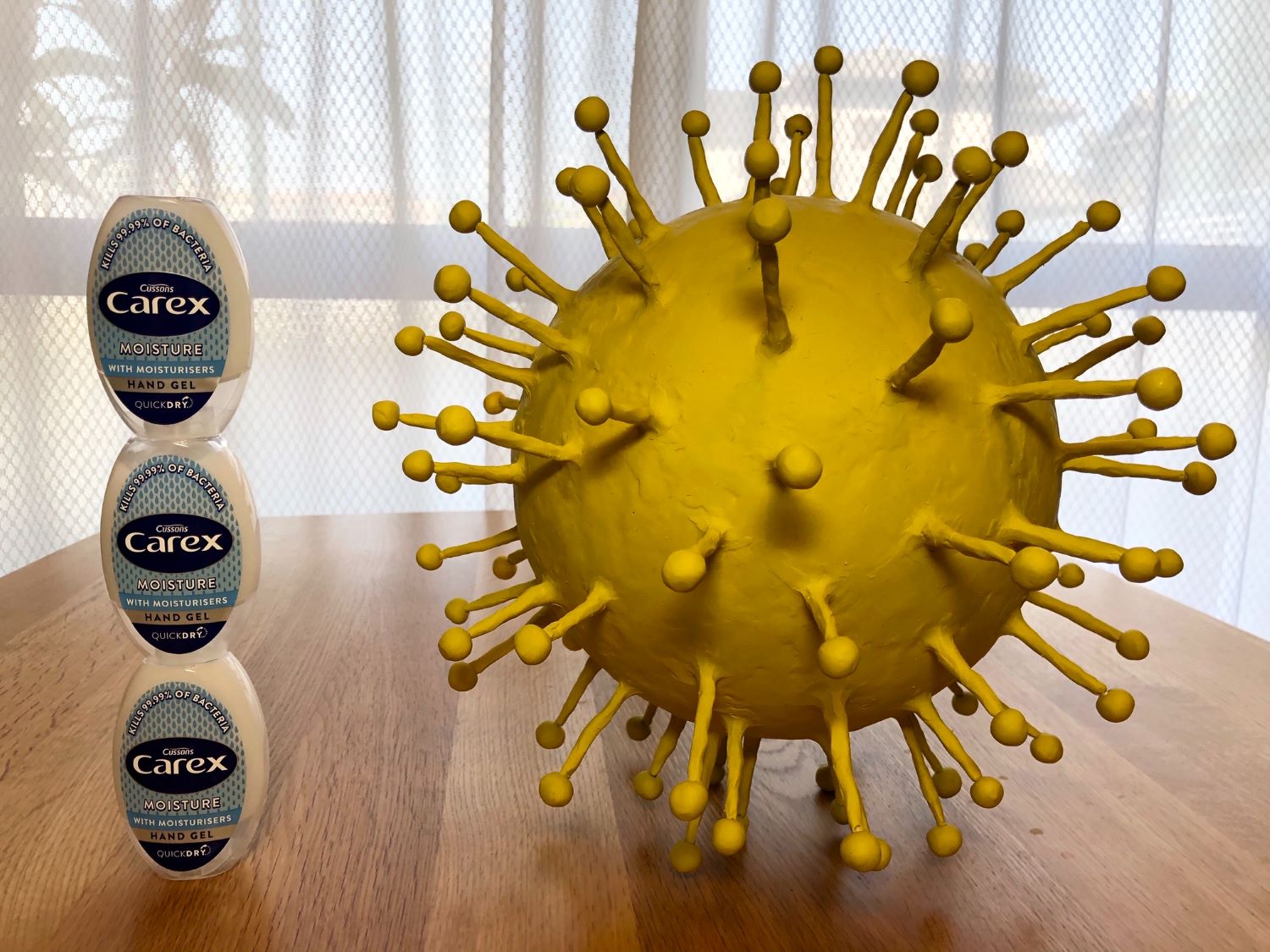 Digital image of large yellow virus cell on table with hand sanitiser