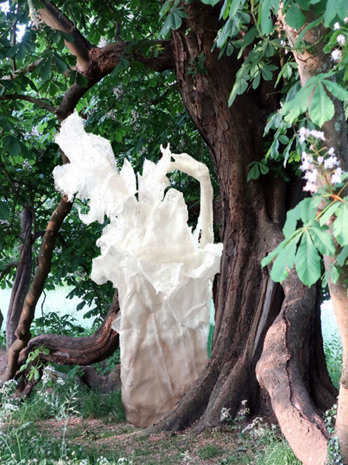 White fibreglass sculpture next to tree